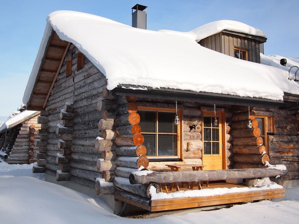 A snow-covered cabin against a blue sky background