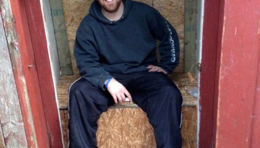 cottage coach adam holman sitting in his rebuilt outhouse