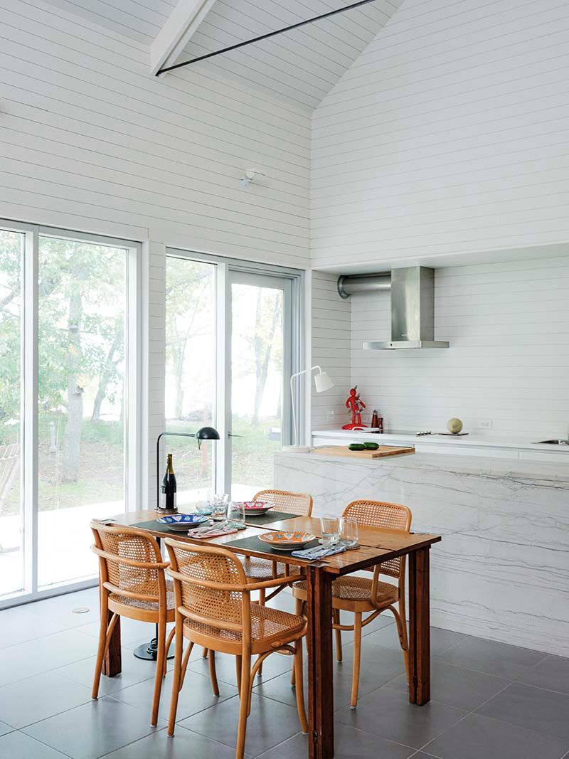 shot of the white interior kitchen with a table and four dining chairs and the lake in the distance