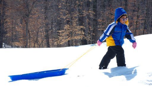 Young girl pulling her sled in the snow, friluftsliv