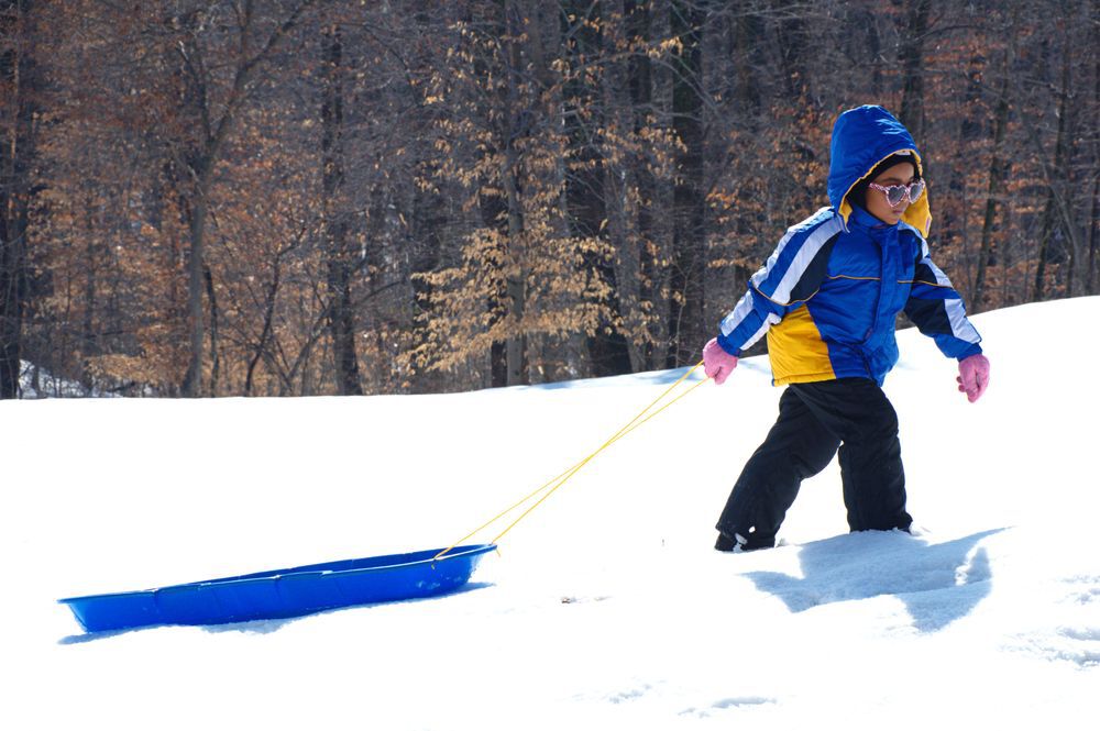 Young girl pulling her sled in the snow, friluftsliv