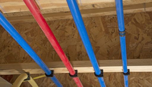 Red and blue PEX pipes attached to a basement ceiling