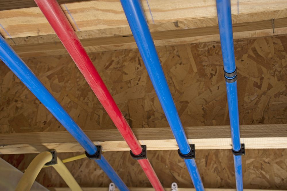 Red and blue PEX pipes attached to a basement ceiling