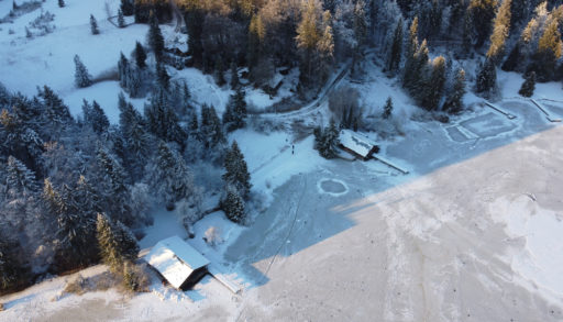 An aerial shot of a frozen lake with docks and boathouses
