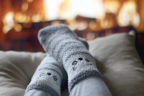 Feet in cute fuzzy socks in front of a fireplace