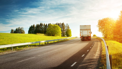 asphalt road on dandelion field with a small truck. lorry moving on sunny evening