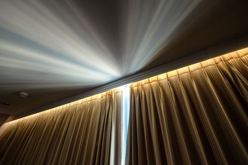 Closed brown heavy curtains getting flooded with light from sun