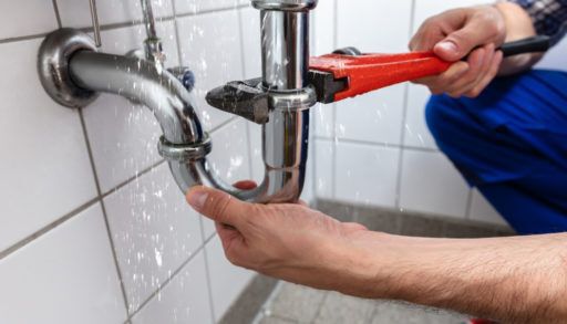 A closeup of the hands of a man fixing a plumbing pipe
