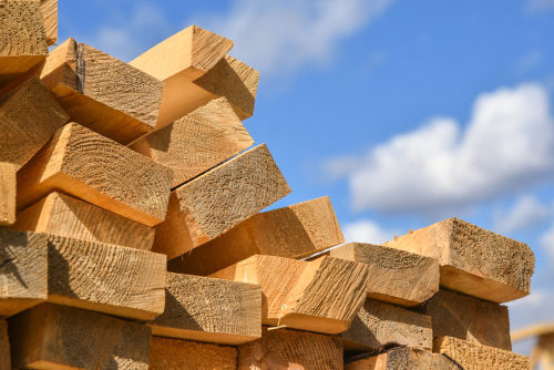 Stacked lumber on blue sky.Folded wood.Closeup wooden boards.The surface of the end of the board.Lots of planks stacked on top of each other in the warehouse.Lumber for use in construction, building materials