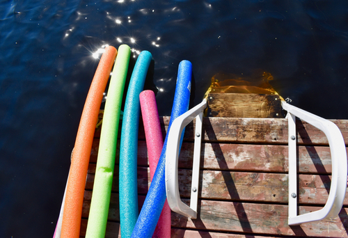 Colorful swimming noodles on a lake dock in the summertime