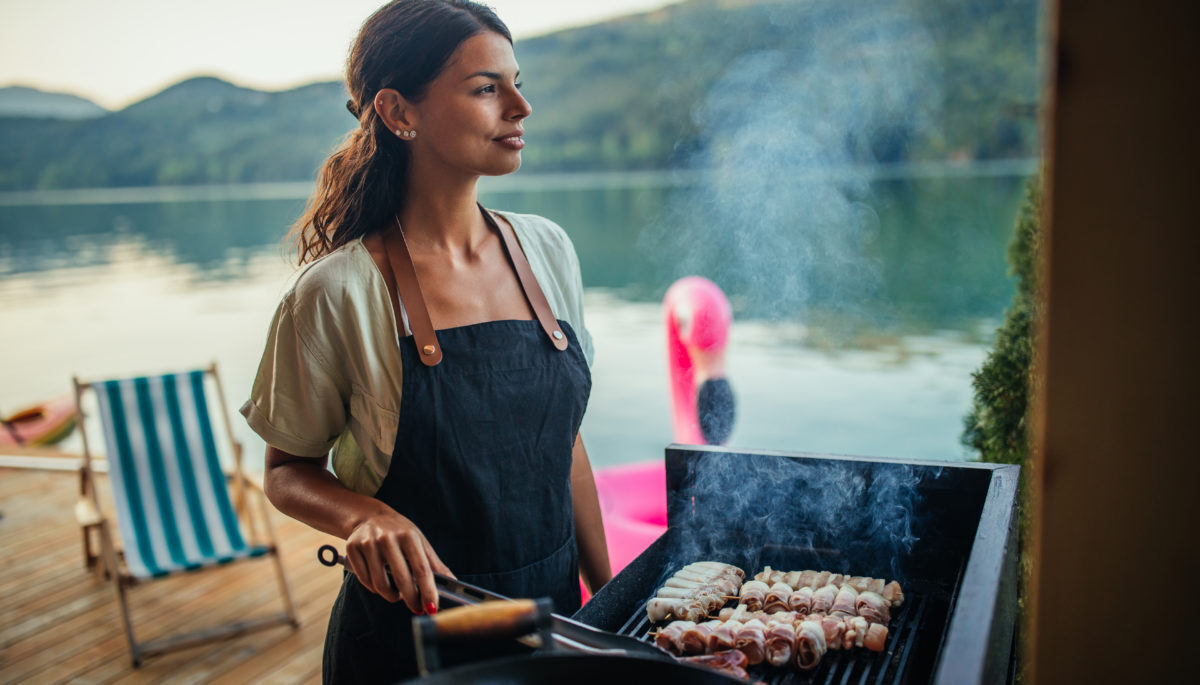 women cooks on grill at cottage with barbecue toolkit