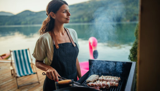 women cooks on grill at cottage with barbecue toolkit