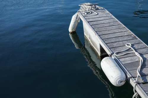 Small floating dock for boats mooring with white fenders