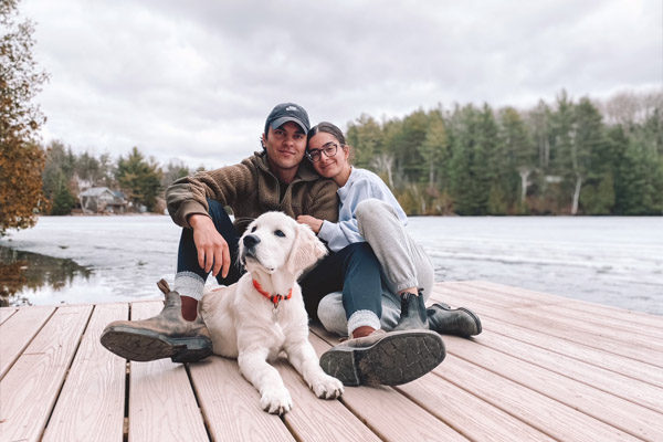 man and woman sitting on a cottage dock with their golden retriever at Crystal Lake