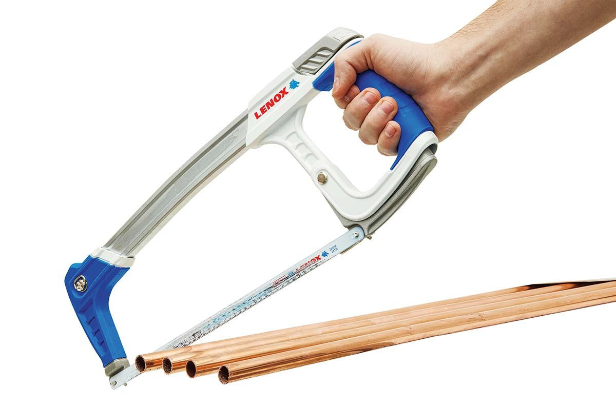 hand holding a high-tension hacksaw cutting copper pipe on white
