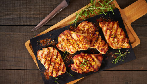 A tray of grilled pork chops on a picnic table