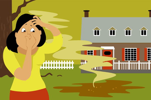 A woman standing in a backyard next to a puddle of sewage, pinching her nose.