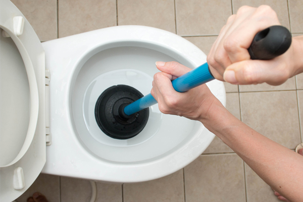 A person using a toilet plunger.