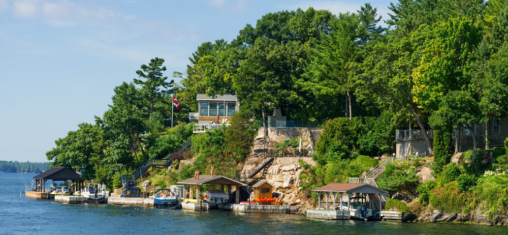 Thousand Islands, Ontario - August 27, 2016: Homes and boathouses on a rocky cliff in Thousand Islands region in Ontario, deal-breakers