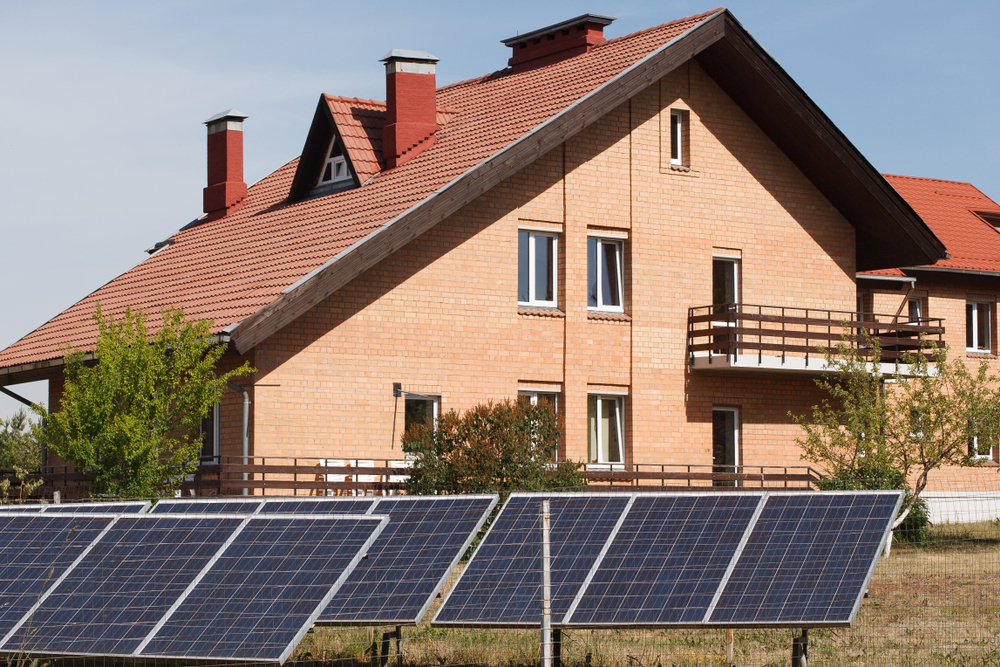 Red brick house with solar panels on the ground.