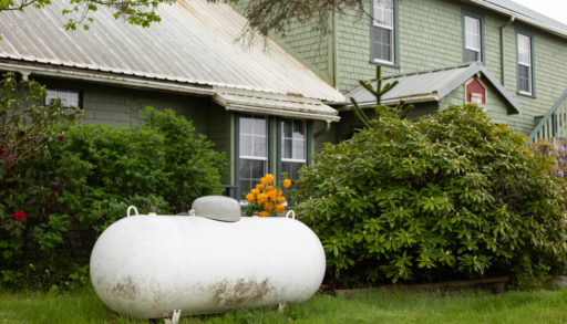 A large propane tank in the yard of a home.