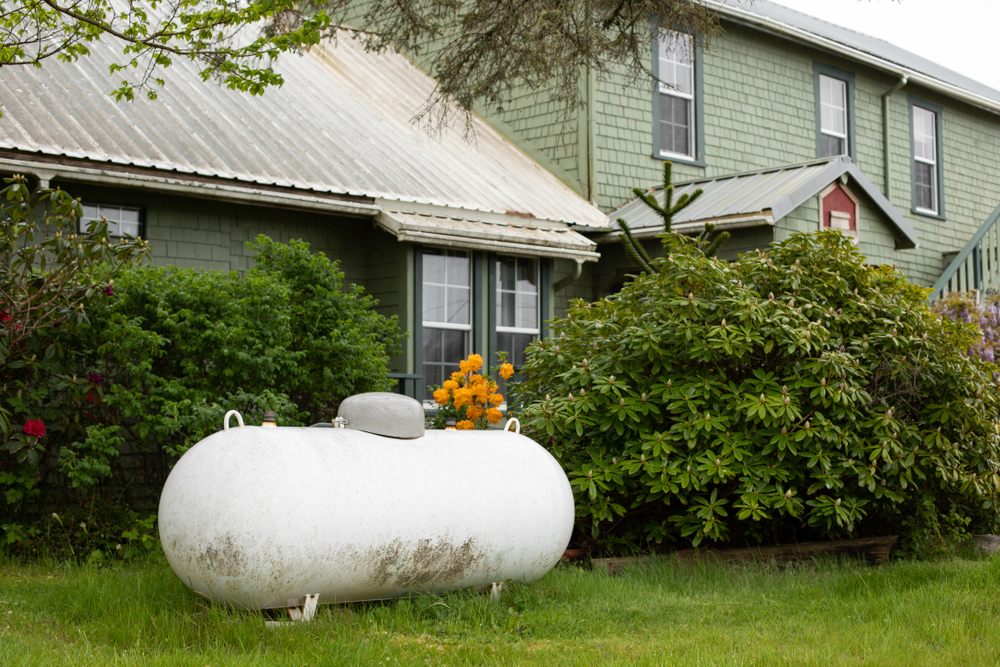 A large propane tank in the yard of a home.
