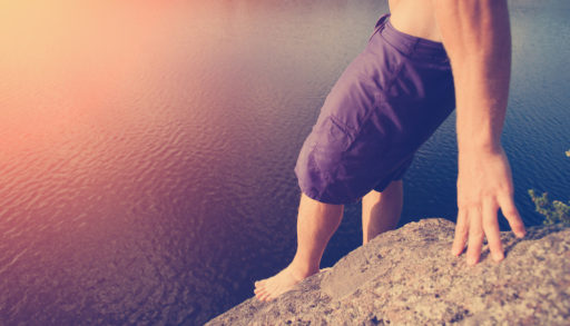 Man preparing to cliff jump into the lake