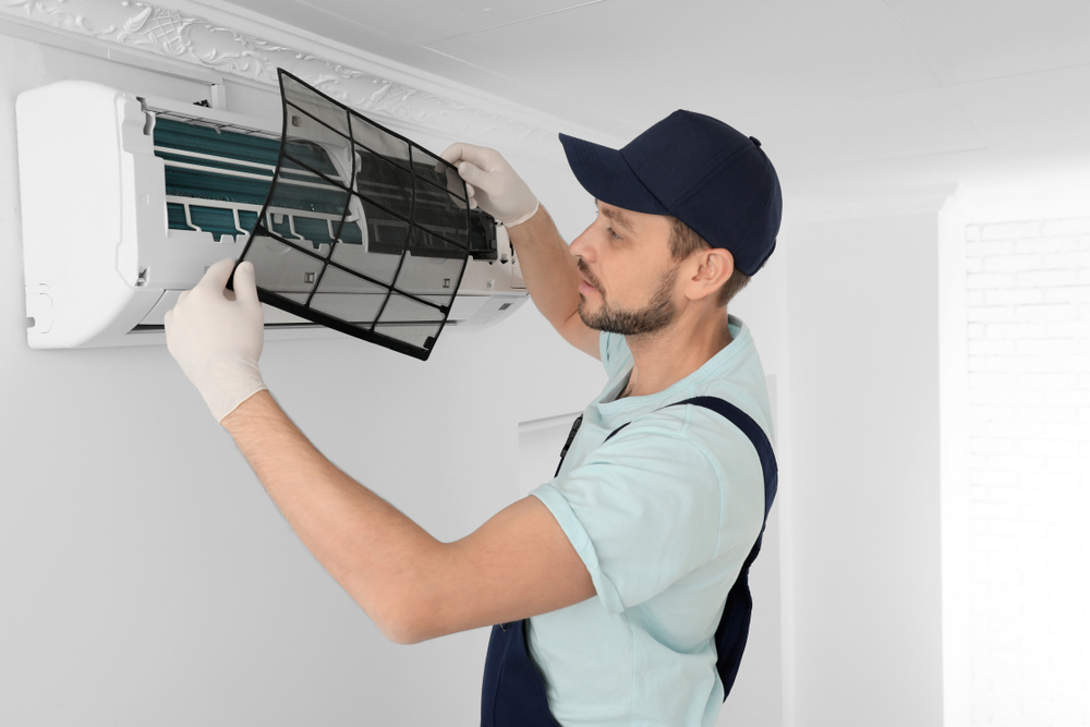 Male technician cleaning air conditioner indoors
