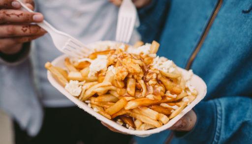Two people eating poutine