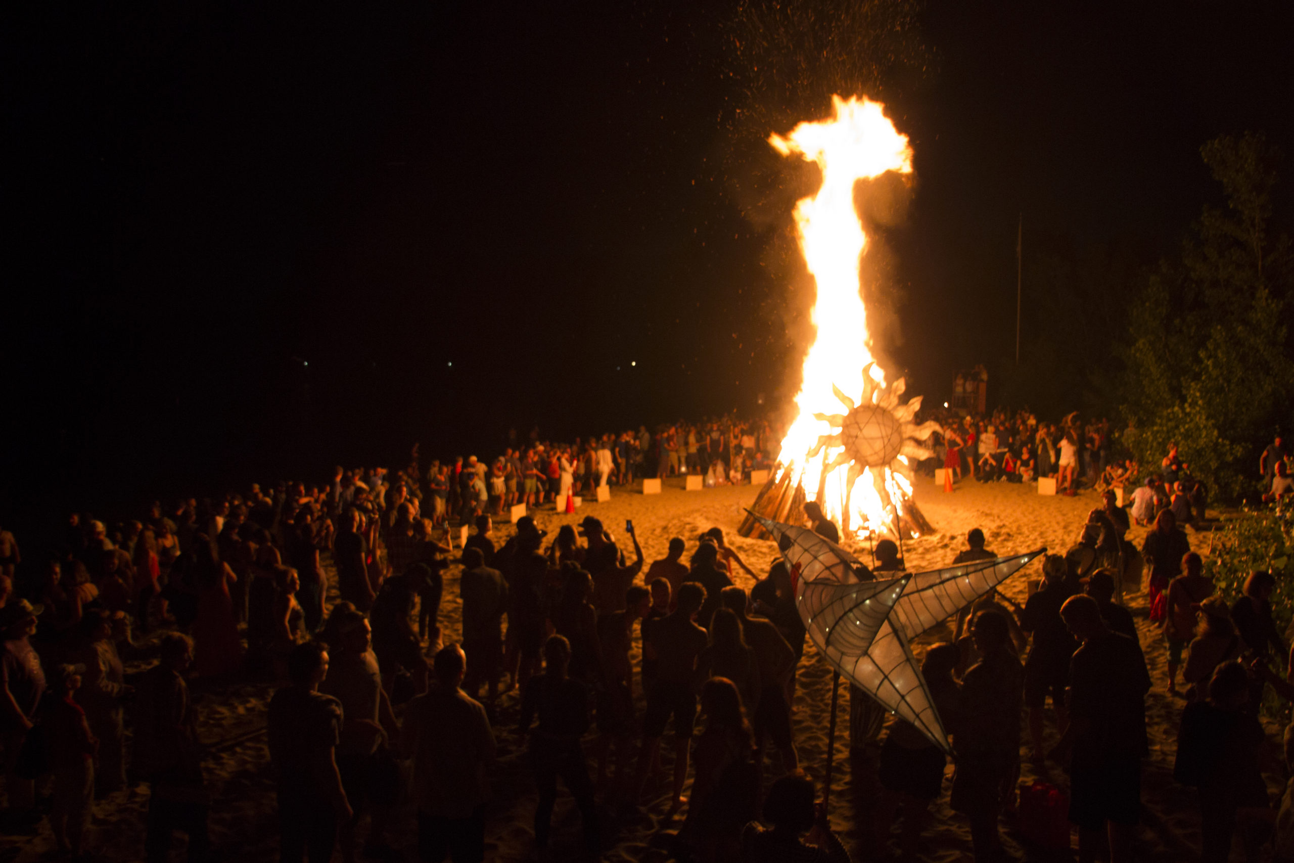 people surround a bonfire on a beach