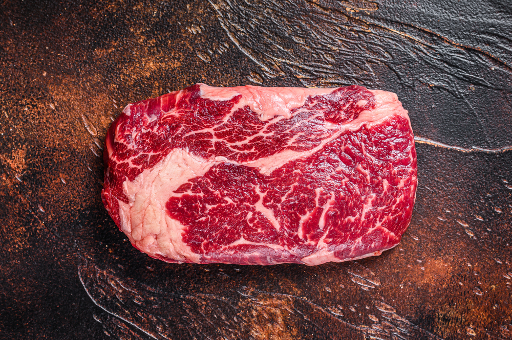 Raw rib eye beef meat steak on a butcher table, septic tank