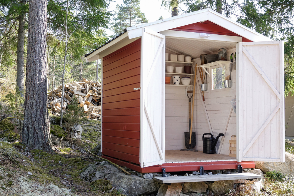 Storage shed filled with garden tools. Shovels, rake, pots, water pitcher and all you need for gardening.