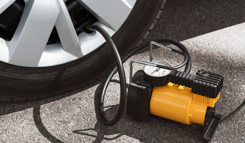 Automobile compressor. Electric pump inflates a car wheel close-up, emergencies