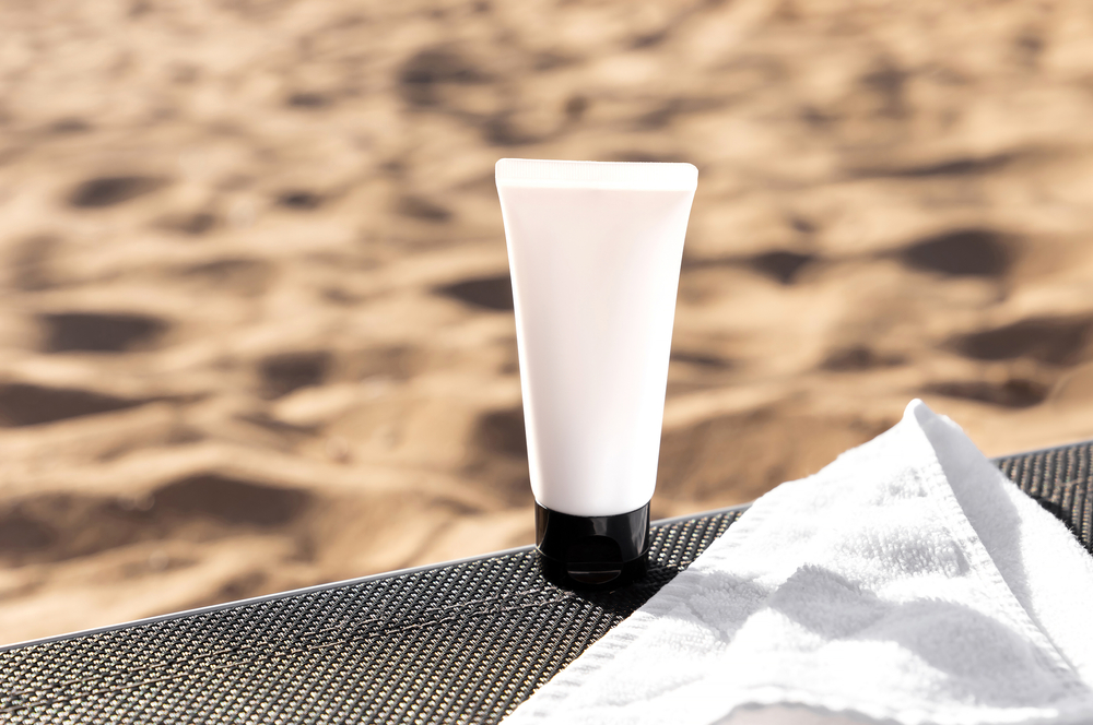 A bottle of sunscreen against a sandy background