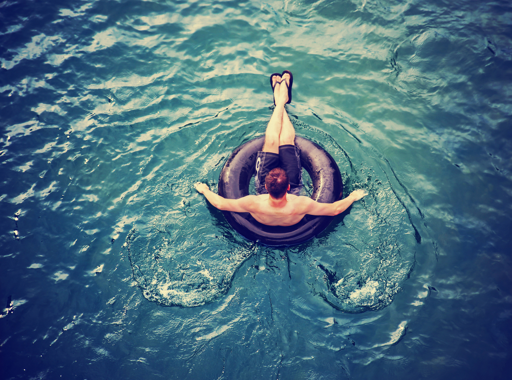 A man floating in the lake on a black inflatable tube