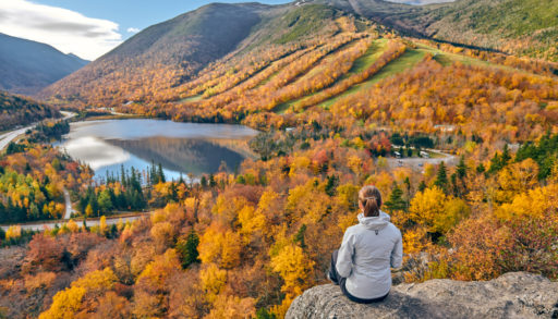 Woman sitting on cliff looking at fall foliage