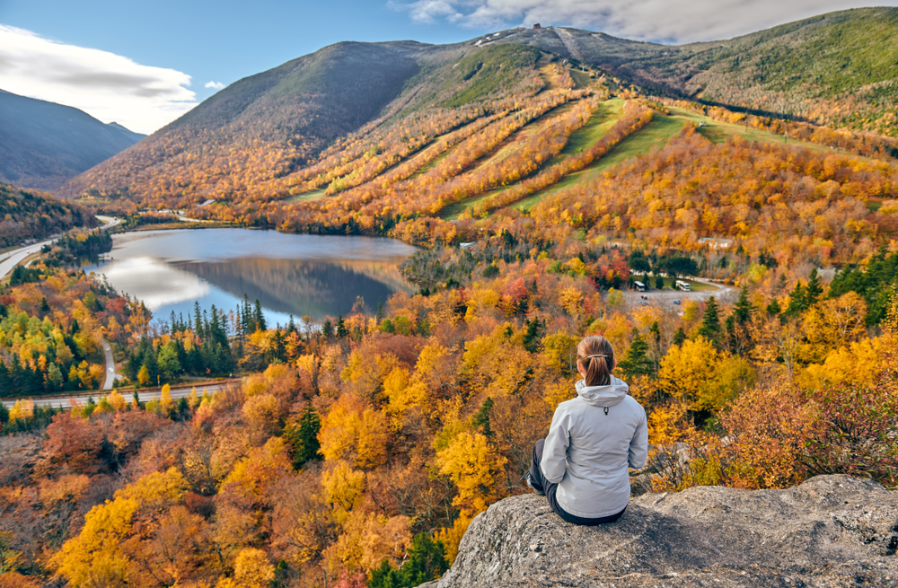 Woman sitting on cliff looking at fall foliage