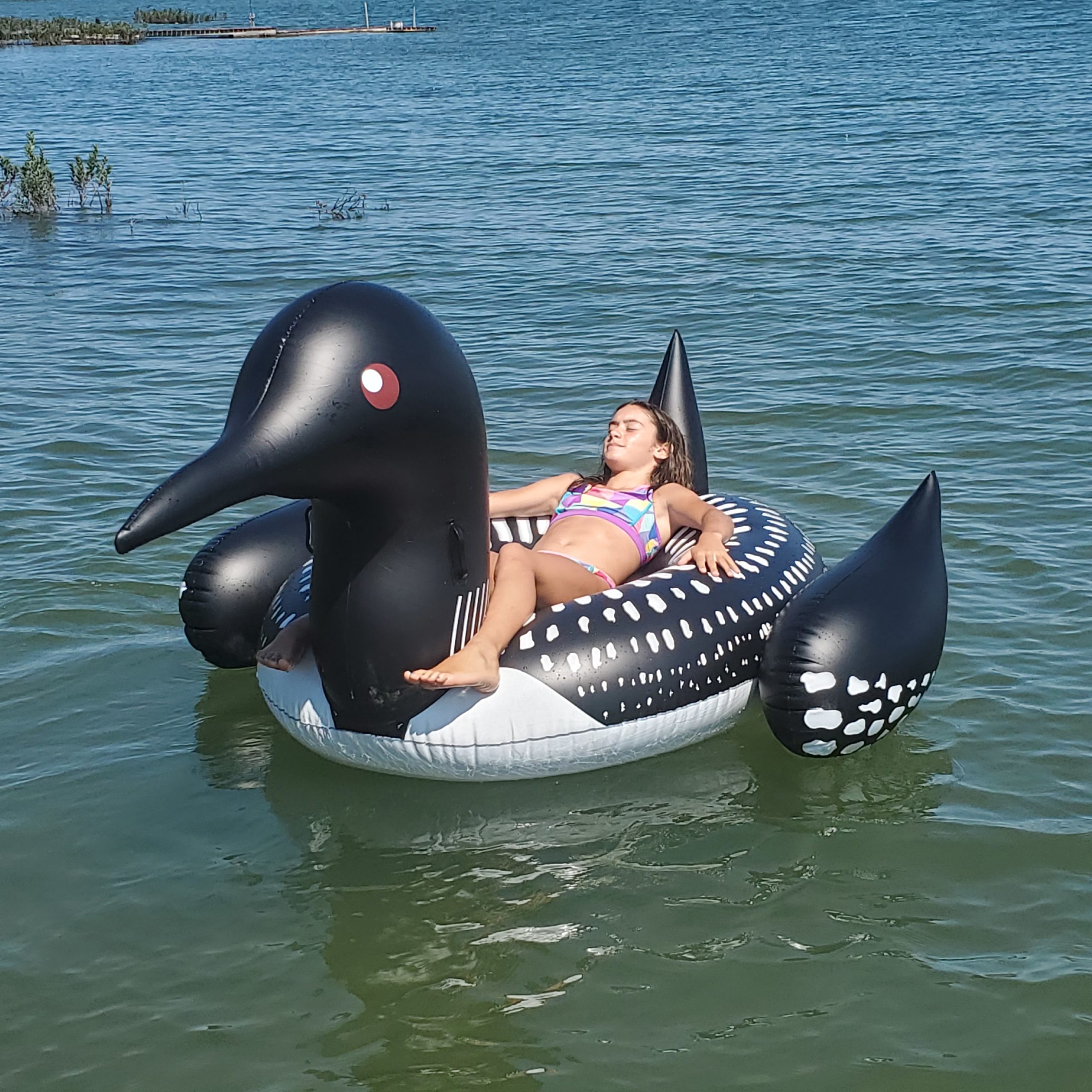 Girl relaxing on loon float on the lake