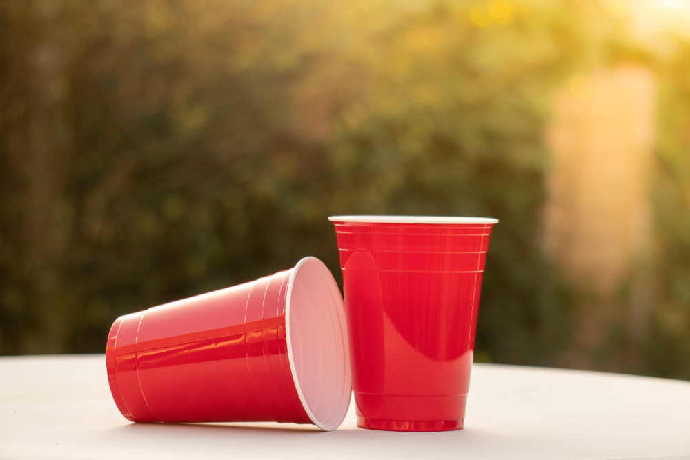 Plastic red solo drinking cups for beer pong or drinking games with green background on a white table, measure