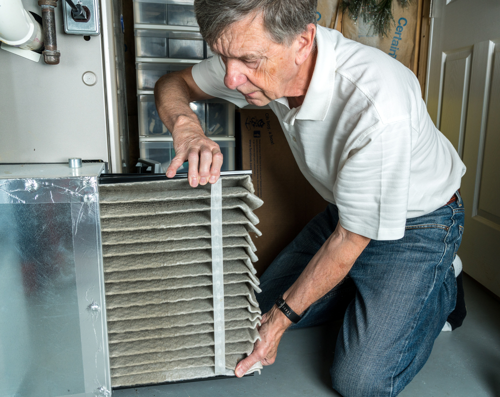 A man changing a dirty air filter, heating