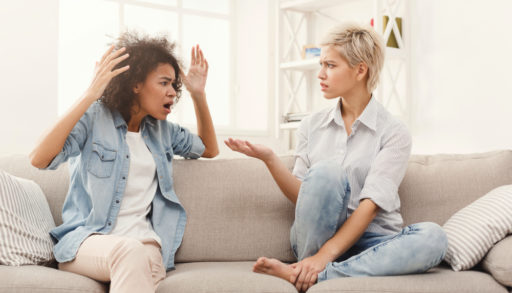 Two women sitting on a couch, having an argument