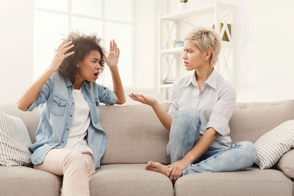 Two women sitting on a couch, having an argument