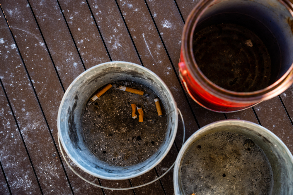 buckets and paint cans filled with sand being used as ashtrays outdoors