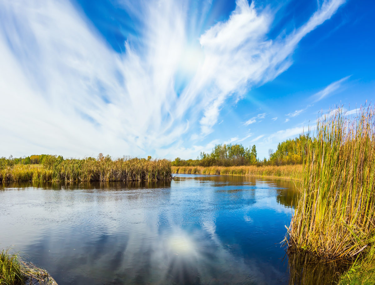 Old Pinawa Dam Provincial Heritage Park. The weak northern autumn sun and some thin cirrus clouds are reflected in the Winnipeg River, near Lac du Bonnet.