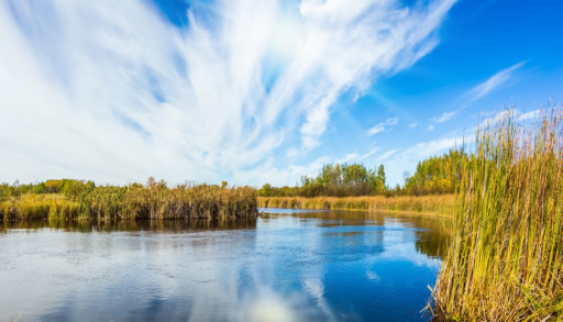Old Pinawa Dam Provincial Heritage Park. The weak northern autumn sun and some thin cirrus clouds are reflected in the Winnipeg River, near Lac du Bonnet.