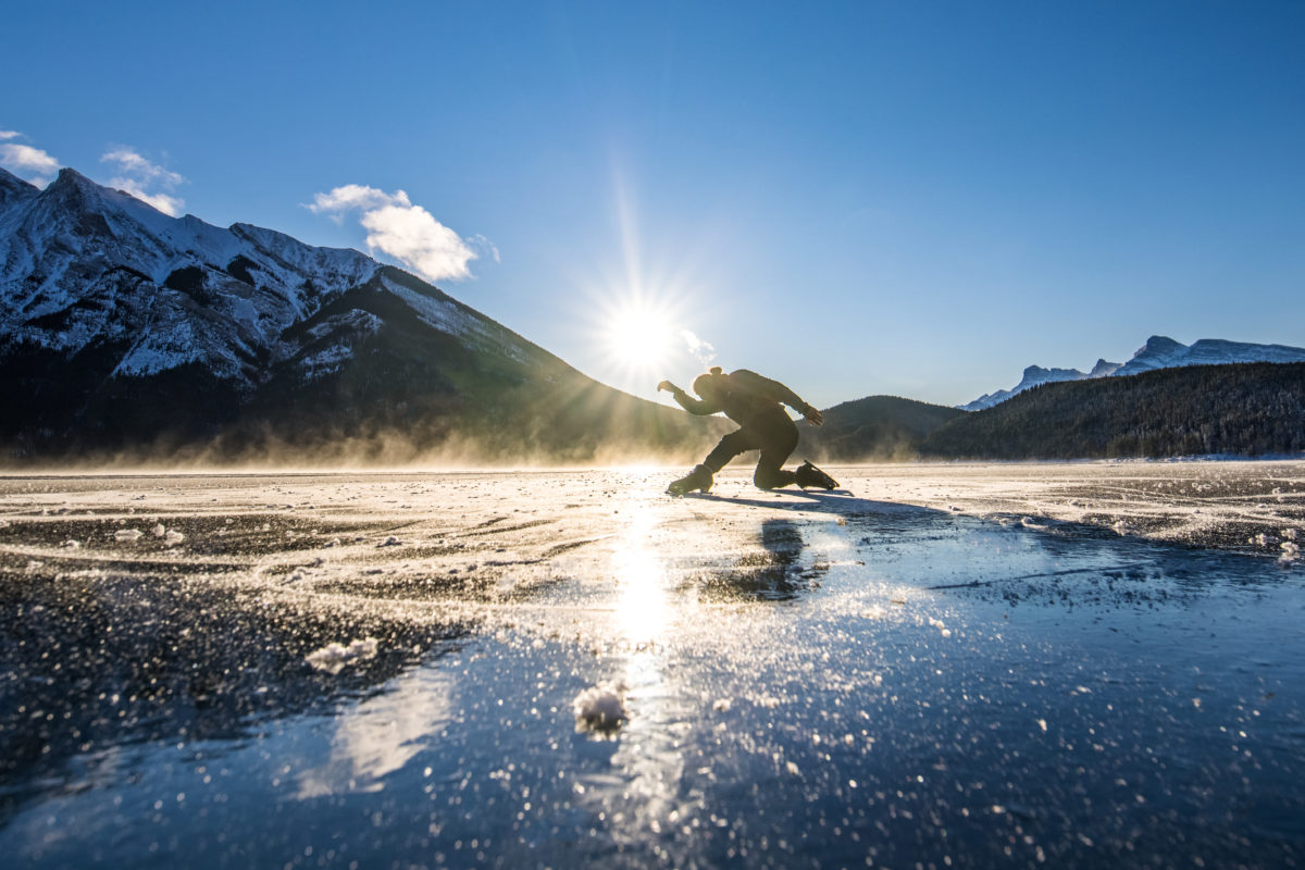 Elladj Balde gets ready to skate on a frozen lake in the mountains with the sunrise behind