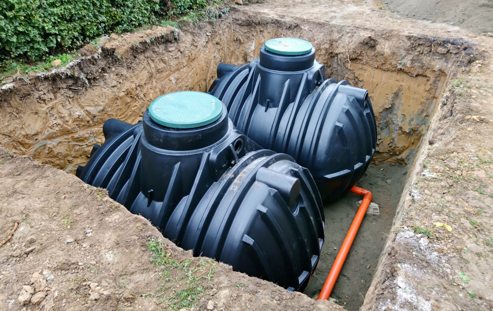 Two plastic holding tanks in a sand pit