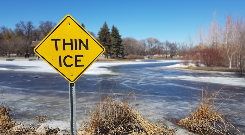 yellow thin ice sign by frozen lake