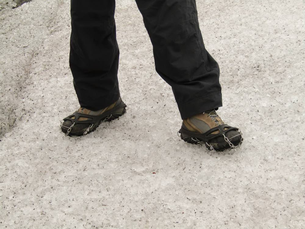 Close-up of pair of legs and boots with ice cleats