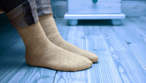 Female legs in woolen socks, standing on a grey floor